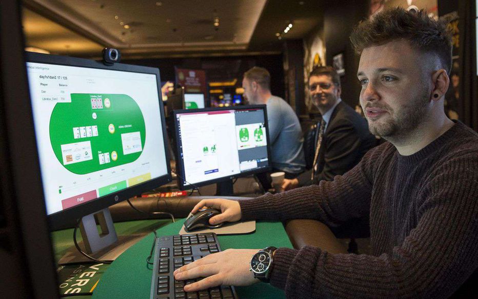 A poker pro plays heads-up online against the Libratus AI on dual monitors at a casino event.