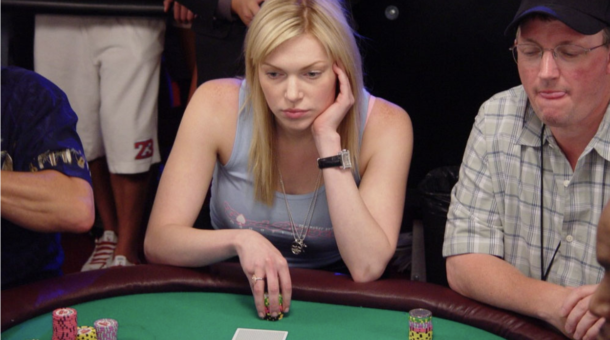 Laura Prepon rests her chin on her hand, eyeing the action at a crowded WSOP table.